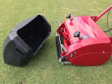 A black resin-made grass collector box detached from red mowing machine.