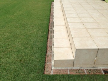 Bricks laid around the lawn. Around the tile terrace.