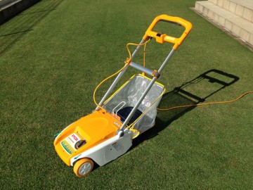 A yellow mower, Ryobi LM-2800. In front of the green lawn.