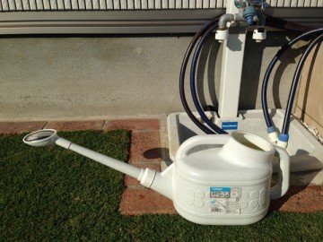 Full of the diluted solution in a 6 L watering pot. In front of the garden tap stand.