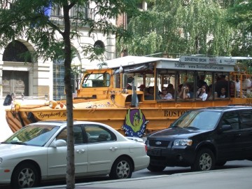 A yellow amphibious bus of Boston Duck Tours driving in the city of Boston.