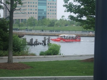 A red bus of Boston Duck Tours floating on the water of Charles River.
