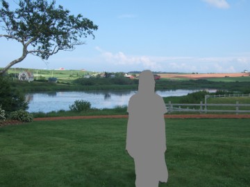 A lawn in Prince Edward Island. River, farm, and blue sky are behind the green lawn.