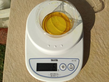 量りの上の透明なカップに黄色いアルムグリーンの原液が6g。
